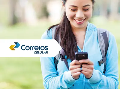 Mulher em um local aberto vestindo blusa azul e mochila nas costas sorri enquanto segura e olha o celular. Centralizado o texto Correios Celular